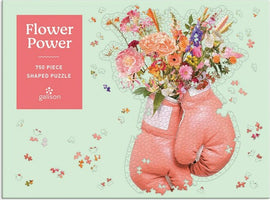 The Flower Power Shaped Puzzle by Galison features a vibrant design of a bouquet of flowers emerging from pink boxing gloves. This 750-piece jigsaw puzzle has a unique shape, adding an element of challenge and enjoyment to assembling it. The cheerful colors and floral motif make it a delightful addition to any puzzle collection.