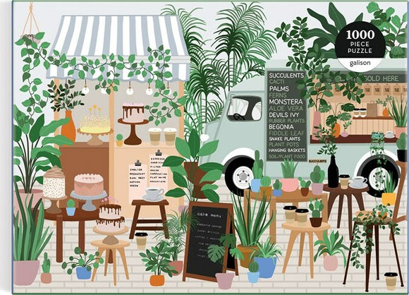 A colorful and intricately illustrated jigsaw puzzle titled 'Plant Cafe' by Galison. The scene depicts a vibrant outdoor cafe filled with various plants, including succulents, palms, and ferns. Beautiful desserts are displayed on wooden tables, enhancing the inviting atmosphere. A charming food truck is visible in the background, adorned with signage detailing plants and cafe offerings. The puzzle consists of 1000 pieces, perfect for plant lovers and puzzle enthusiasts alike.
