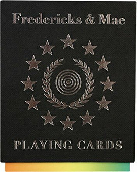Fredericks & Mae Playing Cards featuring an elegant black cover embossed with a circular design surrounded by stars and laurel leaves. The title 'PLAYING CARDS' is prominently displayed at the bottom, making it a stylish addition to any game night.
