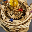 Close-up view of the Starry Night Music Box Build Kit by Robotime, featuring intricate wooden gears and colorful glass-like beads. This DIY kit showcases a celestial theme with star engravings and a whimsical, steampunk aesthetic.