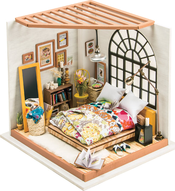 A detailed model kit of a dreamy bedroom featuring a bed with colorful bedding, a section for books with decorative items, a large mirror, potted plants, and cozy lighting. The room is designed with wall art and a beautiful window that allows natural light to illuminate the space.