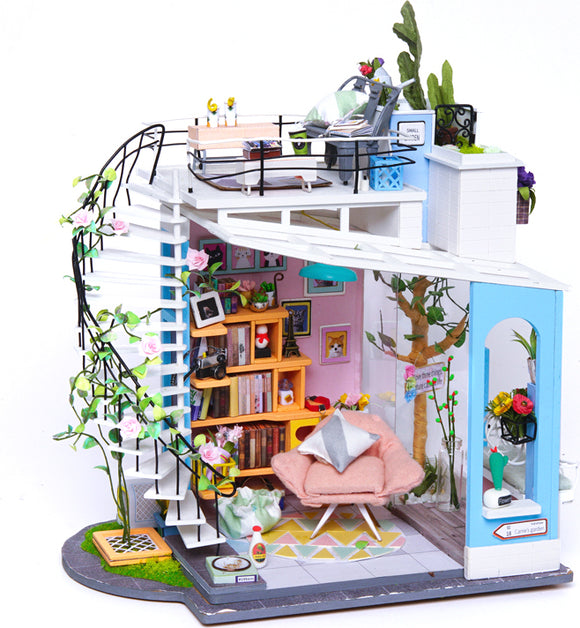 Dora's Loft DIY Model Kit by Robotime. This detailed miniature model features a two-story design with a cozy living room, a stylish bookshelf, a pink armchair, and a rooftop deck adorned with potted plants. Intricate details such as wall art and decorative items enhance the charm, making it an ideal DIY project for hobbyists.