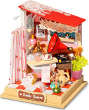 A detailed model kit of a cozy Bubble Bath bathroom scene. The intricate setup features a red roof, a bathtub, a shower curtain with pink accents, decorative bottles, a gramophone, and vibrant plants. Perfect for DIY enthusiasts to create and showcase a charming miniature space.