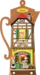 The Lazy Coffee House DIY kit by Robotime features a charming wooden coffee shop model with a detailed facade. It showcases a welcoming entrance, vibrant colors, and playful decorations, including a cute figure and a coffee menu sign. Ideal for hobbyists and crafting enthusiasts, this kit offers a relaxing build experience.