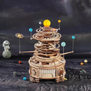 Curious Discovery Solar System Model Kit by Robotime, a DIY mechanical model showcasing a rotating solar system with planets and an intricate gear system, set against a cosmic background.