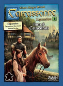 Carcassonne: Expansion 1 – Inns & Cathedrals game box featuring a medieval scene with a man, a woman, and a horse by a river. The box indicates that the Carcassonne base game is required to play. Designed by Klaus-Jürgen Wrede and published by Z-Man Games, this expansion adds new gameplay elements to the classic tile-placing game.