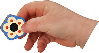 A person’s hand holding a colorful, flower-shaped magnetic piece from the Magnetic Book Moduloform by Janod. The piece features a floral design with a black center and bright colors, perfect for engaging tactile play.