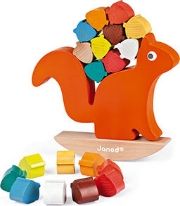 The Nutty Balance Balancing Game by Janod features a brightly colored orange squirrel with a collection of acorns balanced on its back. The game includes various shaped acorns in colors like blue, red, yellow, and brown, placed on a wooden rocking base. This engaging balance game encourages fine motor skills and hand-eye coordination for young children.