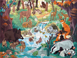 The Footprint Seek & Find Puzzle by Janod features a vibrant and colorful jigsaw scene depicting a forest filled with various animals including deer, foxes, and ducks near a flowing stream. The illustration includes rich greenery, mushrooms, and detailed animal characters, creating an engaging and educational experience for children as they search for different animal silhouettes within the puzzle.