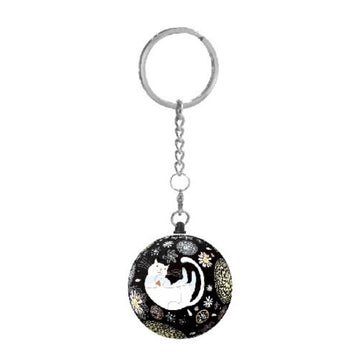 A whimsical keychain featuring a jigsaw puzzle design of a sleeping white cat surrounded by colorful abstract patterns on a black background. The keychain is attached to a silver chain and metal ring, making it a charming accessory for cat lovers.