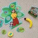 Monkey Around: the Wiggle and Giggle Game by MindWare features a colorful tree and playful monkey graphics. The game includes cards with 'Solo' and 'Together' activities, plush banana, and a vibrant game board designed for fun, interactive play for kids.