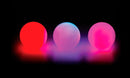 Three LED juggling balls from Wes Peden by Fun in Motion Toys (Spinballs) glowing in different vibrant colors: red, blue, and pink, set against a black background. These playful, colorful balls are perfect for juggling enthusiasts and provide an entertaining light show.