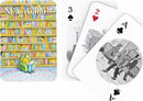 A set of playing cards featuring whimsical illustrations related to literature. The card backs showcase colorful book spines against a library backdrop, while the face cards depict imaginative scenes, including a person reading and others engaging in literary activities. This artistic design is perfect for book lovers and game enthusiasts alike.