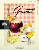 Cheese Tasting Jigsaw Puzzle featuring a vibrant illustration of assorted cheeses, a wine glass, and a red bowl, set against a checkered background. The design is a detailed artwork by Henry Stahlhut, showcasing the delightful themes of gourmet cheese.