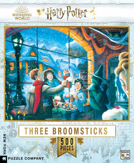 A colorful jigsaw puzzle box featuring a vibrant scene from the Harry Potter universe. It depicts characters enjoying a warm moment inside the Three Broomsticks, surrounded by winter decor and festive ambiance. The box includes 500 pieces, promising hours of fun for fans of all ages.