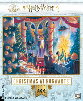 A 500-piece jigsaw puzzle titled 'Christmas at Hogwarts' from the New York Puzzle Company, featuring a festive scene at Hogwarts School of Witchcraft and Wizardry. The image depicts a cheerful holiday gathering with decorations, a Christmas tree, and characters celebrating around a table filled with treats. The vibrant colors and magical atmosphere capture the essence of Christmas in the wizarding world.