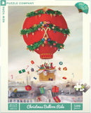 A festive jigsaw puzzle featuring a vibrant red hot air balloon, decorated with greenery and Christmas ornaments, ascending over a snowy town. Below the balloon, colorful gifts and candy canes float through the air, creating a cheerful holiday scene. The puzzle consists of 500 pieces and is produced by New York Puzzle Company.