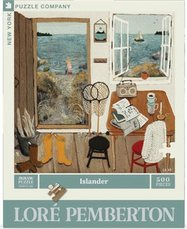 Islander jigsaw puzzle by New York Puzzle Company featuring a cozy scene of a seaside home. The illustration depicts an open door with a child in striped clothes standing by the water, surrounded by fishing nets, boots, a table with books, a candle, and a scenic view of boats on the water. The puzzle contains 500 pieces and is designed by Loré Pemberton.