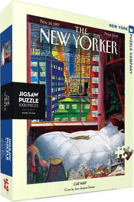 Box of the Cat Nap Jigsaw Puzzle (1000 pieces) by New York Puzzle Company featuring a whimsical illustration by Jean-Jacques Sempé, showcasing a cozy scene with a comfortable bed and a playful cat. The artwork captures the essence of relaxation and warmth, perfect for puzzle enthusiasts.