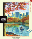 A 500-piece jigsaw puzzle titled 'Central Park Row' featuring a serene autumn scene with a couple rowing in a blue boat on a reflective lake surrounded by vibrant orange and yellow foliage, illustrated by Eric Drooker. The puzzle's box shows colors of fall with skyscrapers in the background, providing a picturesque view of Central Park.