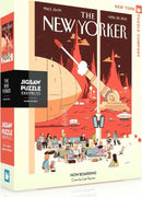 The box of the Now Boarding Puzzle, a 1000-piece jigsaw puzzle by New York Puzzle Company. The artwork features a vibrant, whimsical scene depicting a busy airport terminal with various characters waiting, surrounded by an imaginative landscape with a large airship and futuristic elements. The cover illustration is by Luke Pearson, with the title 'NOW BOARDING' prominently displayed.