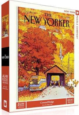 The Covered Bridge Puzzle, a 1000-piece jigsaw by New York Puzzle Company, features a vibrant autumn scene illustrated by Arthur Getz. The box showcases a picturesque covered bridge surrounded by colorful fall foliage, a vintage bus, and people enjoying the serene landscape.