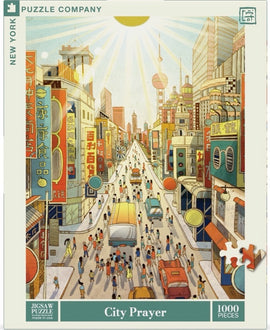A colorful, bustling city scene featured on the jigsaw puzzle titled 'City Prayer' by New York Puzzle Company. The illustration shows a vibrant urban street filled with people, vehicles, and shop signs in various languages. The sun shines brightly overhead, illuminating the busy atmosphere and details of the city life. This jigsaw puzzle consists of 1000 pieces, offering a challenging and enjoyable experience for puzzle enthusiasts.