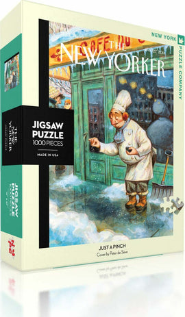 The Just a Pinch jigsaw puzzle from New York Puzzle Company features a whimsical illustration by Peter de Séve, depicting a chef in a snowy street scene with vibrant colors and engaging details. The puzzle contains 1000 pieces and comes in a stylish box showcasing the artwork on the front.