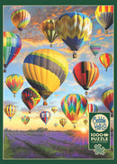A colorful jigsaw puzzle featuring a stunning scene of numerous hot air balloons floating above a vibrant lavender field with a beautiful sunset in the background. The puzzle consists of 1000 pieces and includes a poster for reference. Made by Cobble Hill, this puzzle offers a delightful and engaging experience for puzzle enthusiasts.