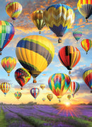 A vibrant image of multiple colorful hot air balloons soaring through a bright sky at sunset. Below, a field of lavender flowers stretches into the horizon, enhancing the scenic beauty of the moment. The balloons display intricate patterns and bright colors, creating a joyful and uplifting atmosphere.