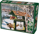 Cobble Hill's Backyard Banquet jigsaw puzzle featuring a picturesque winter scene with a bird feeder surrounded by various birds, a rustic barn in the background, and snow-covered trees. The puzzle contains 1000 pieces and includes a poster for reference.