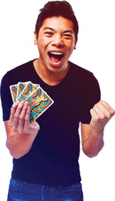 A young man enthusiastically holds up a set of colorful cards from the game WordSpiel. He is wearing a black shirt and has an animated, joyful expression on his face, with his mouth open in a smile and his fist raised in excitement.