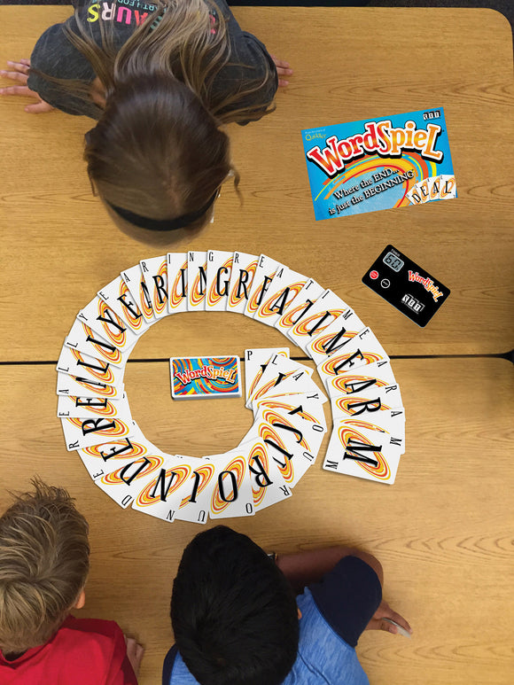 A top view of children playing WordSpiel, a fun word game by Set Games. The colorful cards are arranged in a spiral pattern on the table, with the game box visible nearby. The playful atmosphere captivates the idea of creativity and wordplay as the kids engage in the game.