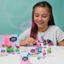 A young girl joyfully creating her own fairy potions with a DIY kit from Craft Tastic. The table is adorned with colorful potion bottles, sparkly beads, and a vibrant backdrop featuring playful fairy illustrations.