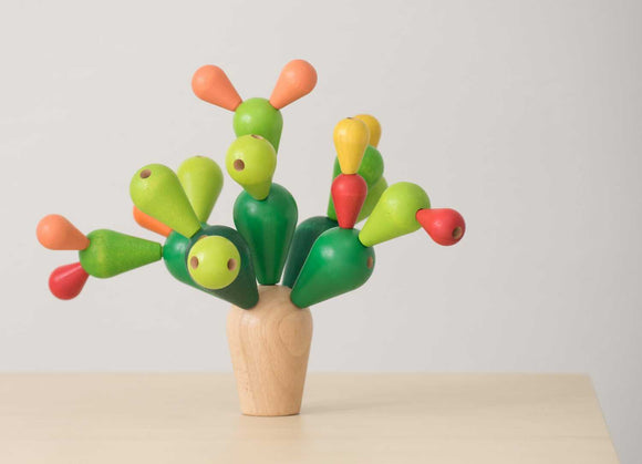A colorful Balancing Cactus game from Plan Toys, featuring vibrant green, red, yellow, and orange wooden pieces arranged to mimic a cactus. Ideal for developing fine motor skills and balance.
