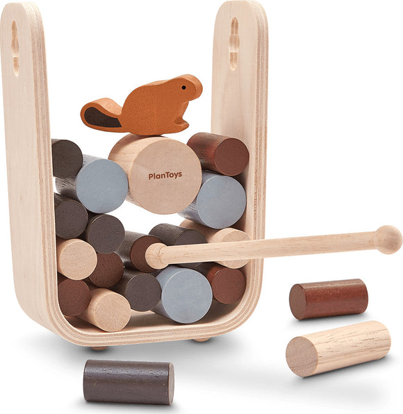 Timber Tumble game by Plan Toys featuring a wooden structure with colorful cylindrical blocks stacked inside. A beaver figure sits atop the stack, and a wooden mallet is included for play. The design promotes balance and dexterity for children.