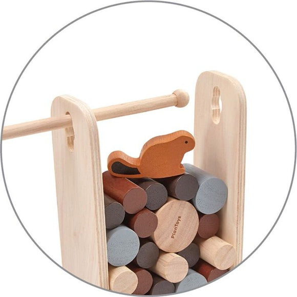 Timber Tumble game by Plan Toys features a wooden frame with a red-brown beaver character resting on top of colorful, cylindrical wooden blocks stacked inside. This engaging stacking game encourages fine motor skills and creative play for children.