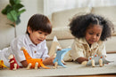 Two children playing on a carpet, assembling colorful Brachiosaurus DIY kits. They are focused on creating and enjoying the playful dinosaur figures made from wood and colorful materials.