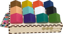 Chroma Cube by Project Genius features a collection of twelve colorful, geometrically shaped wooden pieces arranged on a wooden display base. Each piece displays a different vibrant color, including pink, yellow, green, and blue, facilitating various mechanical puzzle-solving challenges and enhancing spatial reasoning skills.