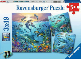 Ravensburger jigsaw puzzle titled 'Ocean Life' featuring vibrant underwater scenes filled with various sea creatures including dolphins, sharks, and colorful fish surrounded by coral reefs. The puzzle is designed for ages 5 and up, showcasing detailed artwork and is available in a 3x49 piece format.