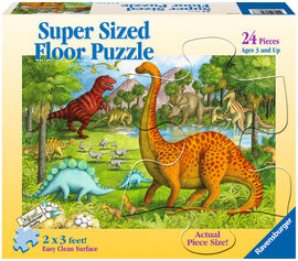 A colorful jigsaw puzzle titled 'Super Sized Floor Puzzle' featuring various dinosaurs in a lush prehistoric scene. The puzzle contains 24 large pieces, suitable for children aged 3 and up. The packaging highlights the dimensions of the completed puzzle, which measures 2 x 3 feet, and emphasizes its easy clean surface.