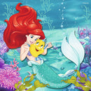 A colorful jigsaw puzzle featuring a vibrant underwater scene with a cheerful red-haired mermaid and her yellow fish companion. The background is filled with coral reefs and bubbles, creating an enchanting aquatic atmosphere, perfect for children and Disney fans.