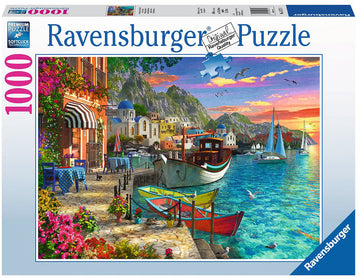 The Grandiose Greece jigsaw puzzle by Ravensburger showcases a stunning Greek waterfront scene. The colorful puzzle features vibrant boats docked by a picturesque harbor, surrounded by charming cafes with outdoor seating, lush flowers, and iconic white and blue buildings with domed roofs. Set against a backdrop of mountains and a beautiful sunset, this puzzle offers 1000 high-quality pieces for a rewarding and relaxing challenge.