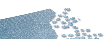 The Krypt Silver jigsaw puzzle by Ravensburger, showcasing a unique circular design with numerous interlocking pieces scattered around, emphasizing a calming monochromatic silver color palette. The image illustrates a section of the incomplete puzzle, inviting enthusiasts to engage in the challenging experience of assembling it.