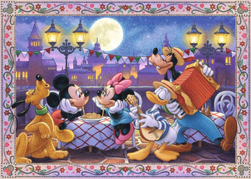 A colorful jigsaw puzzle featuring Mickey Mouse, Minnie Mouse, Donald Duck, Goofy, and Pluto enjoying a festive evening together on a street with decorative lanterns and a full moon. The characters are engaged in cheerful activities, surrounded by tables with food and music in a charming outdoor setting.