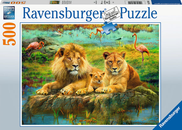 A beautifully illustrated jigsaw puzzle featuring a family of lions – a majestic adult lion and lioness, along with a playful cub – sitting together by a serene water body. The background showcases a vibrant savanna landscape with colorful flamingos and lush greenery, making it a captivating scene for puzzle enthusiasts.