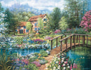 A vibrant jigsaw puzzle featuring a serene landscape scene titled 'Shades of Summer' by Ravensburger. The image displays a charming house with blue shutters, surrounded by a lush garden full of colorful flowers and greenery. A quaint wooden bridge spans over a peaceful stream, enhancing the idyllic setting, while soft clouds float above in a bright sky.