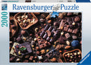 A Ravensburger jigsaw puzzle titled 'Chocolate Paradise' featuring an aerial view of various types of chocolate, nuts, and dried fruits artfully arranged on a wooden table. The puzzle box displays vibrant imagery of the delicious assortment, promising a delightful and challenging experience for puzzle enthusiasts.