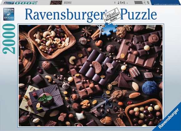 A Ravensburger jigsaw puzzle titled 'Chocolate Paradise' featuring an aerial view of various types of chocolate, nuts, and dried fruits artfully arranged on a wooden table. The puzzle box displays vibrant imagery of the delicious assortment, promising a delightful and challenging experience for puzzle enthusiasts.