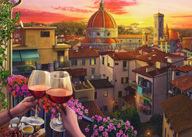 A beautifully illustrated jigsaw puzzle titled 'Cozy Wine Terrace' by Ravensburger. The scene captures a stunning sunset over a quaint Italian city, with vibrant flowers in the foreground, two glasses of red wine clinking together, and a picturesque skyline featuring the iconic dome of a cathedral. This puzzle invites relaxation and enjoyment as you piece together the tranquil ambiance.